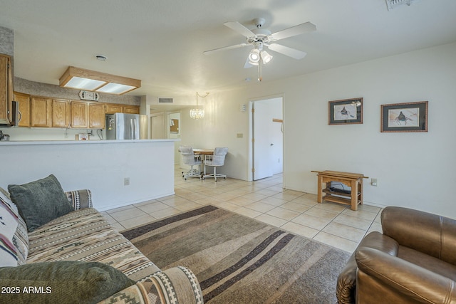 living area with light tile patterned floors, a ceiling fan, a chandelier, and baseboards