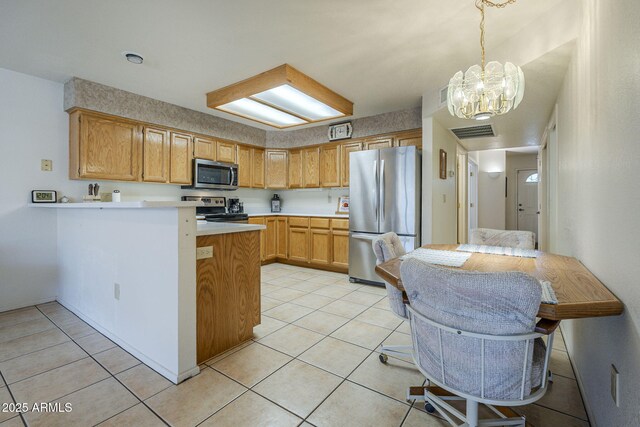 kitchen featuring appliances with stainless steel finishes, a chandelier, light countertops, a peninsula, and light tile patterned floors