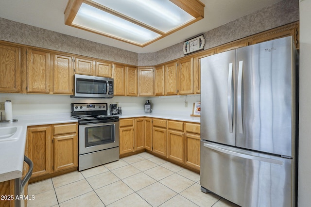 kitchen featuring appliances with stainless steel finishes, light tile patterned floors, light countertops, and a sink