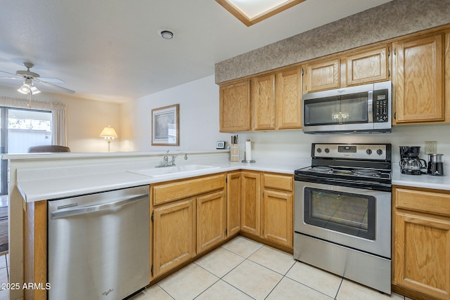 kitchen featuring appliances with stainless steel finishes, a sink, a peninsula, light tile patterned floors, and ceiling fan