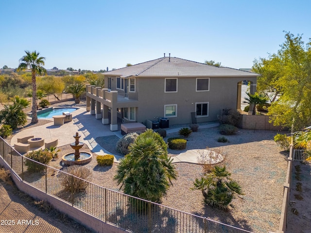 back of property featuring a swimming pool with hot tub and a patio area