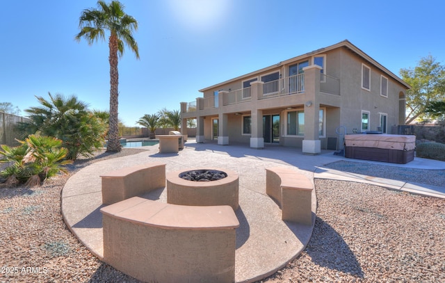 view of patio with a hot tub, a balcony, and an outdoor fire pit