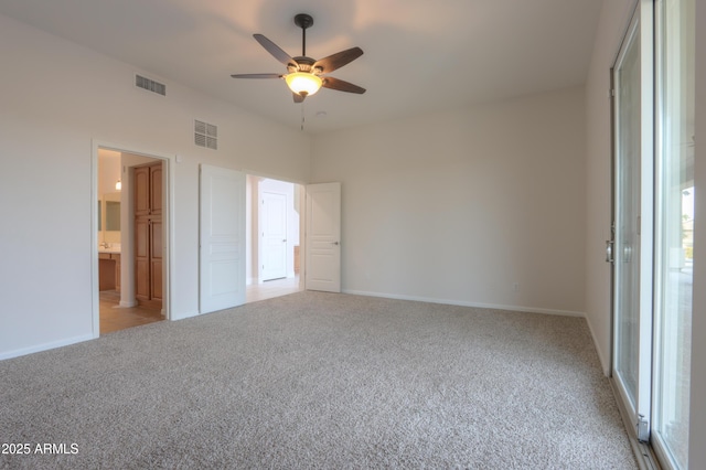 unfurnished bedroom with ceiling fan, ensuite bathroom, and light carpet