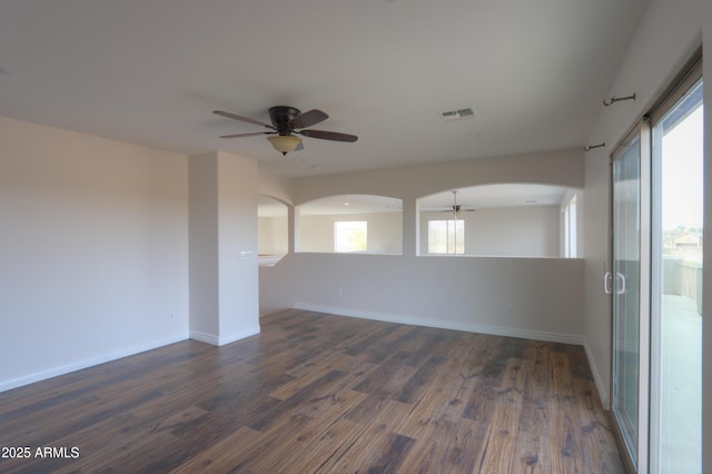 unfurnished room featuring ceiling fan, a healthy amount of sunlight, and dark hardwood / wood-style flooring