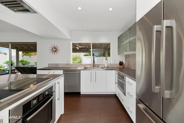 7806 E Via De La Entrada, Scottsdale, AZ 85258 - kitchen with appliances with stainless steel finishes, stainless steel counters, modern cabinets, white cabinetry, and glass insert cabinets