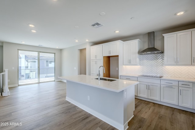 2121 W Sonoran Desert Dr Unit 43, Phoenix, AZ 85085 - kitchen with wall chimney range hood, a sink, light wood finished floors, white cabinetry, and backsplash