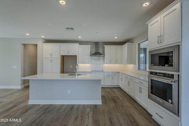 2121 W Sonoran Desert Dr Unit 43, Phoenix, AZ 85085 - kitchen featuring appliances with stainless steel finishes, a sink, wall chimney range hood, backsplash, and a center island with sink