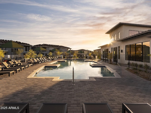 2121 W Sonoran Desert Dr Unit 43, Phoenix, AZ 85085 - pool at dusk featuring a community pool, a patio area, fence, and a residential view