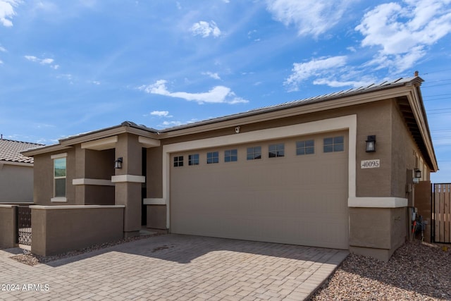 view of front facade featuring stucco siding, an attached garage, decorative driveway, and fence