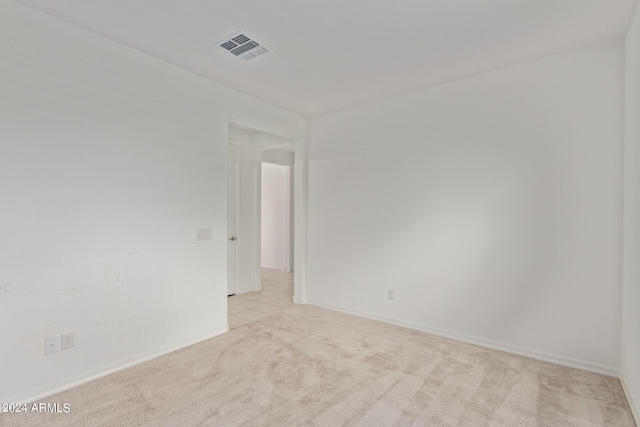 unfurnished room featuring light colored carpet, visible vents, and baseboards