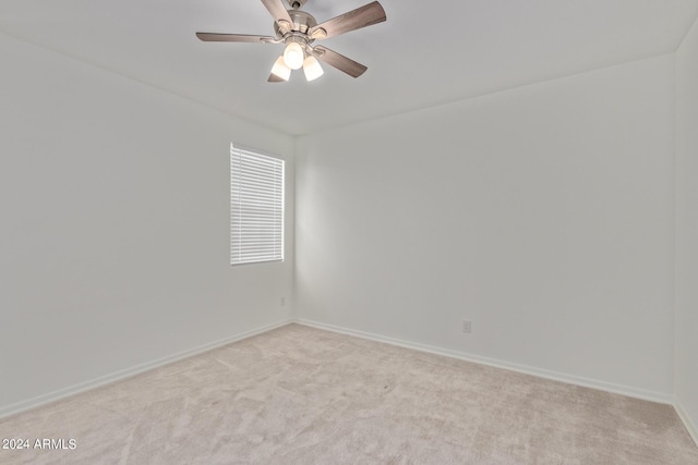 spare room featuring a ceiling fan, light colored carpet, and baseboards