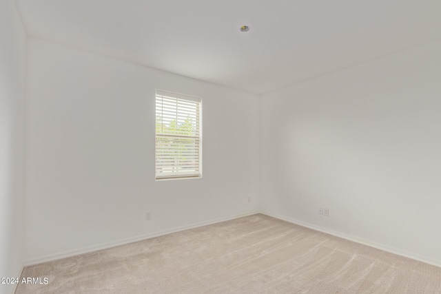 spare room featuring light carpet and baseboards