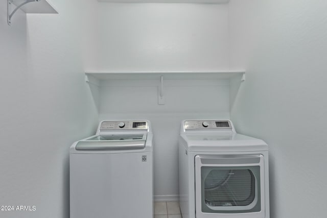 laundry area with separate washer and dryer and light tile patterned floors