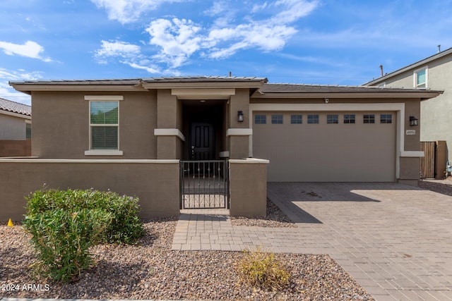 prairie-style house featuring fence, stucco siding, decorative driveway, a garage, and a gate