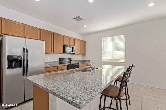 kitchen featuring sink, black appliances, a center island with sink, and light tile patterned floors