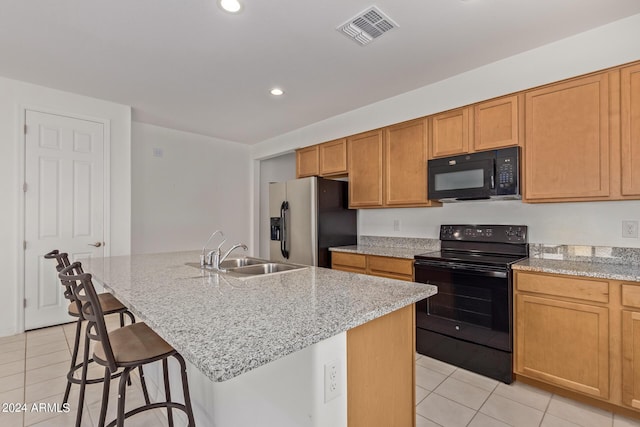 kitchen featuring light tile patterned floors, visible vents, black appliances, and a sink