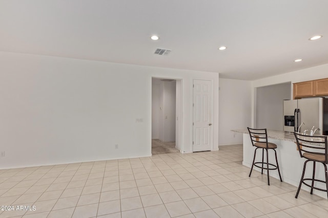 kitchen with visible vents, light tile patterned flooring, recessed lighting, a kitchen breakfast bar, and stainless steel fridge