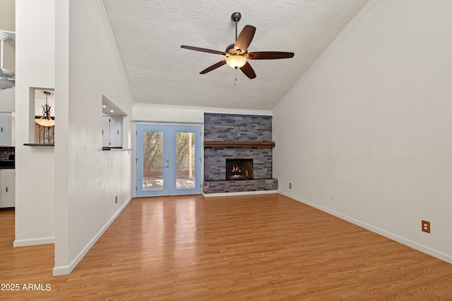 unfurnished living room with a textured ceiling, light hardwood / wood-style flooring, ornamental molding, ceiling fan, and a fireplace