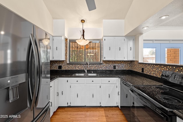 kitchen with sink, black appliances, dark stone countertops, pendant lighting, and white cabinets