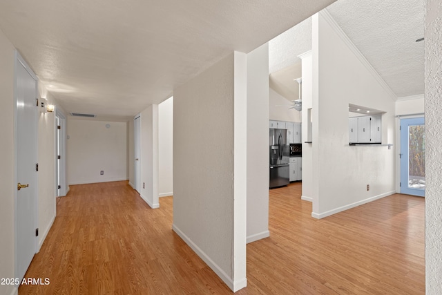 corridor featuring vaulted ceiling, a textured ceiling, and light hardwood / wood-style floors