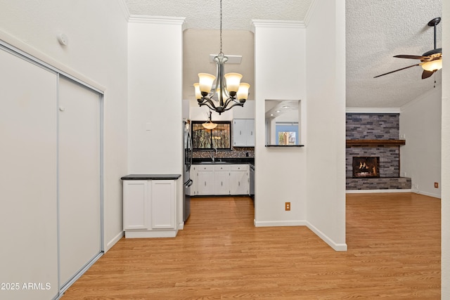 corridor with sink, ornamental molding, a textured ceiling, and light wood-type flooring