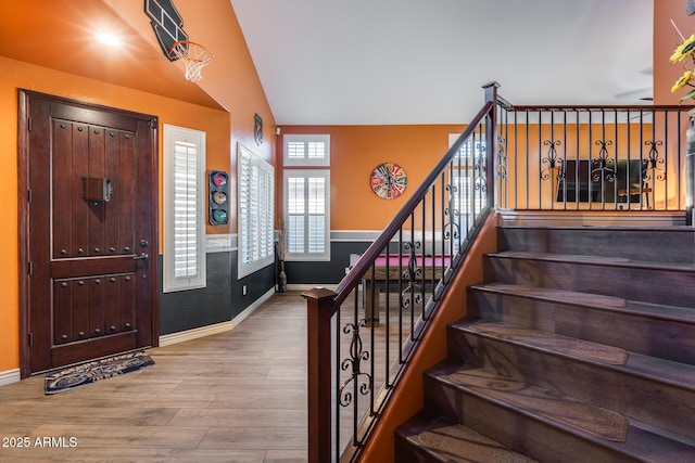 entryway featuring baseboards, stairway, vaulted ceiling, and wood finished floors