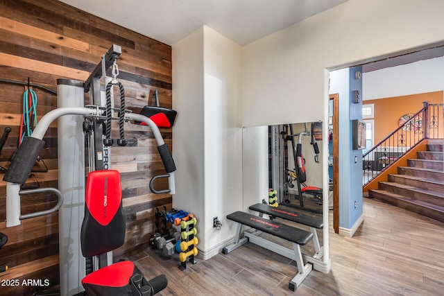 exercise area featuring wood walls and wood finished floors