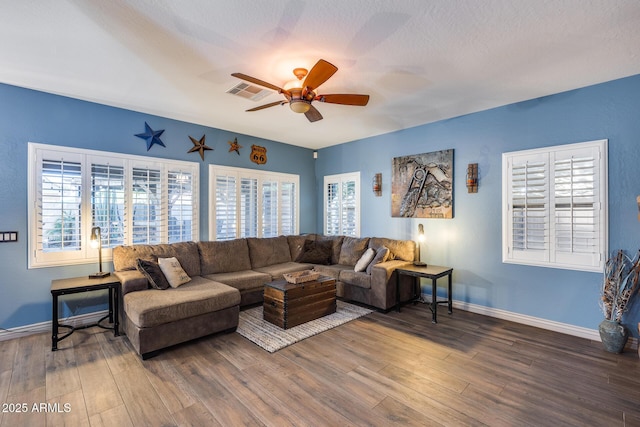 living room featuring wood finished floors, baseboards, ceiling fan, and visible vents