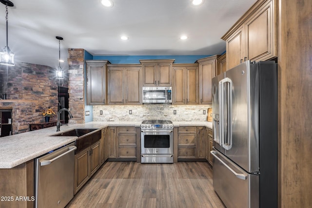 kitchen with dark wood-style flooring, a peninsula, tasteful backsplash, appliances with stainless steel finishes, and a sink