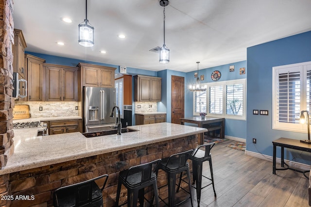 kitchen with high quality fridge, a sink, backsplash, wood finished floors, and baseboards