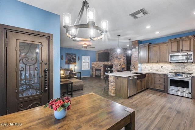 kitchen featuring open floor plan, stainless steel appliances, a sink, visible vents, and a peninsula