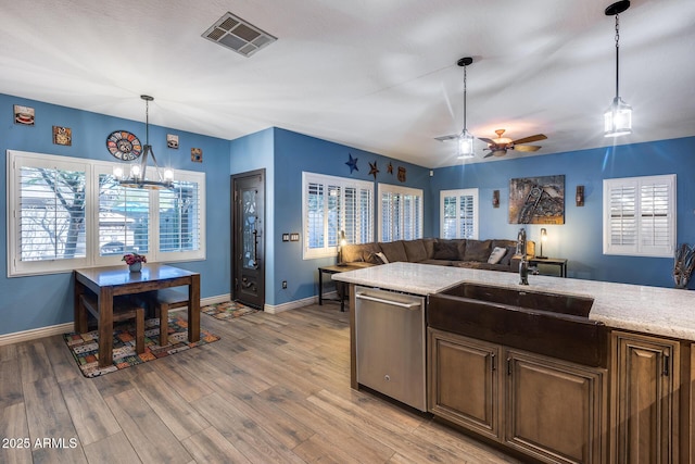 kitchen with a sink, dishwasher, light wood-type flooring, ceiling fan with notable chandelier, and visible vents