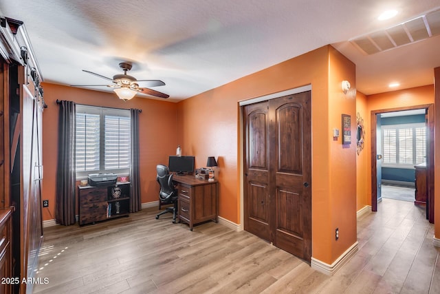 office featuring a wealth of natural light, light wood-style floors, and ceiling fan