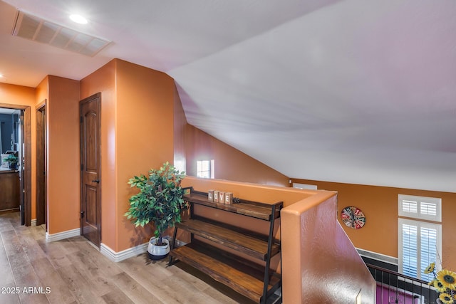 interior space with baseboards, lofted ceiling, visible vents, and wood finished floors