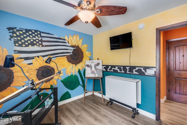 interior space with baseboards, wood finished floors, and ceiling fan