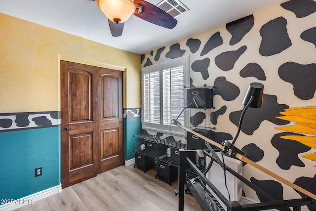 office space featuring a ceiling fan, baseboards, light wood finished floors, and visible vents