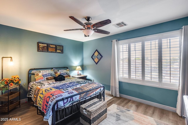 bedroom with baseboards, visible vents, wood finished floors, and ceiling fan