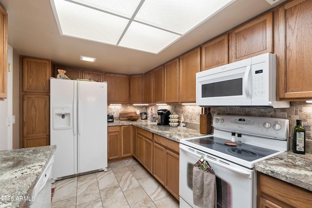 kitchen with decorative backsplash, light tile patterned flooring, light stone countertops, and white appliances