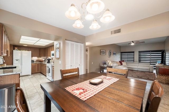 dining area with sink, light tile patterned floors, and ceiling fan with notable chandelier