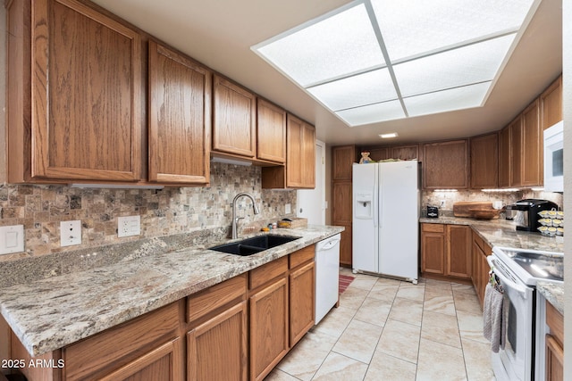 kitchen featuring white appliances, backsplash, sink, light stone countertops, and light tile patterned floors