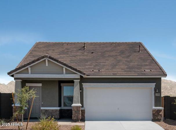 view of front of home with a tile roof, stucco siding, a garage, stone siding, and driveway