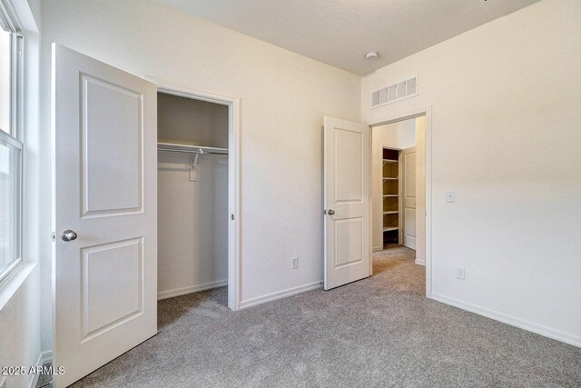 unfurnished bedroom with carpet, visible vents, a closet, and baseboards