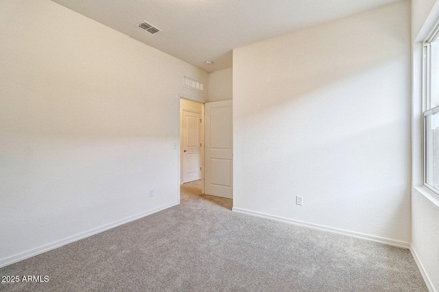 carpeted empty room with a healthy amount of sunlight, visible vents, and baseboards