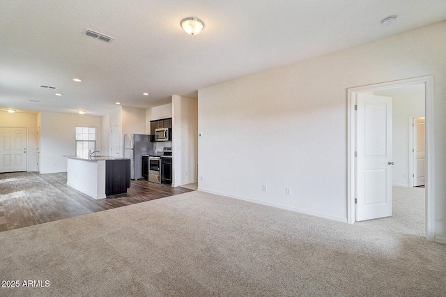 unfurnished living room featuring visible vents, baseboards, recessed lighting, a sink, and dark colored carpet