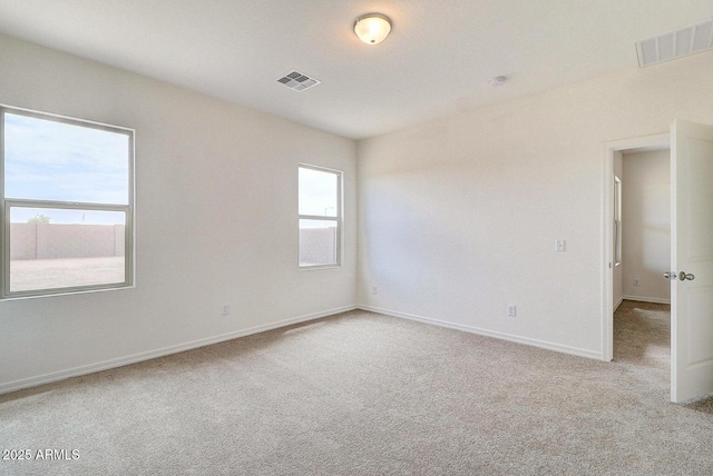 carpeted empty room featuring baseboards and visible vents