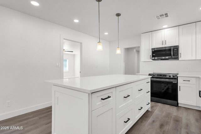 kitchen with range with electric cooktop, decorative light fixtures, a kitchen island, and white cabinets