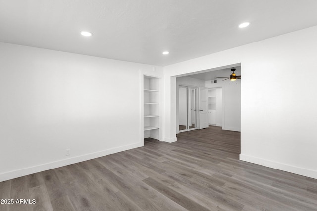 unfurnished room featuring dark hardwood / wood-style flooring, built in features, and ceiling fan