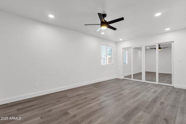 unfurnished bedroom featuring multiple closets, ceiling fan, and hardwood / wood-style flooring