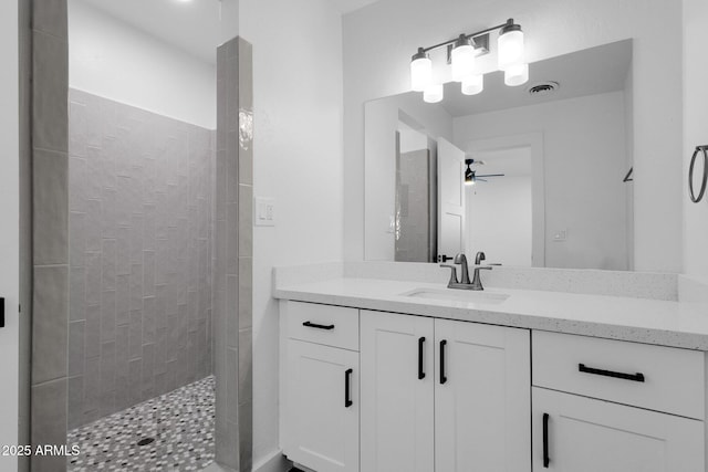 bathroom featuring ceiling fan, tiled shower, and vanity