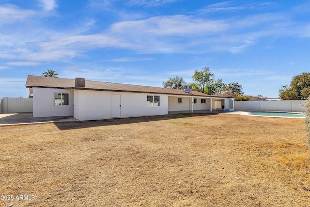 back of property with a yard, a fenced in pool, and a patio